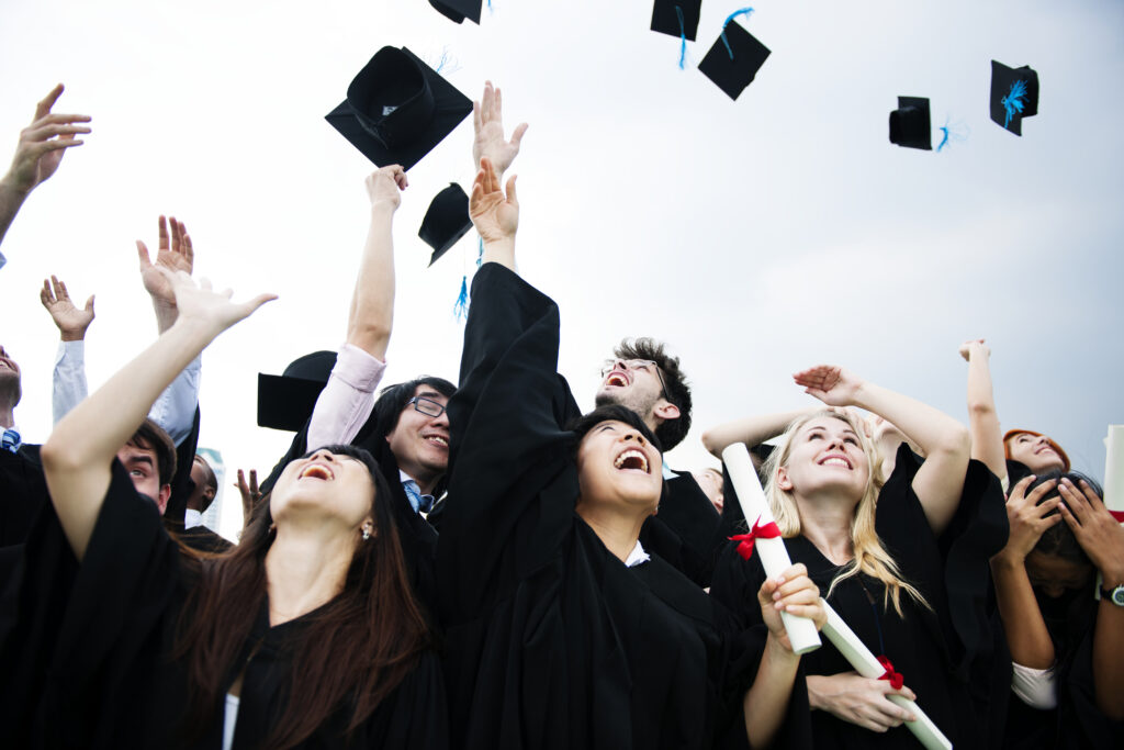 College students celebrating new graduate jobs, throwing caps in the air.