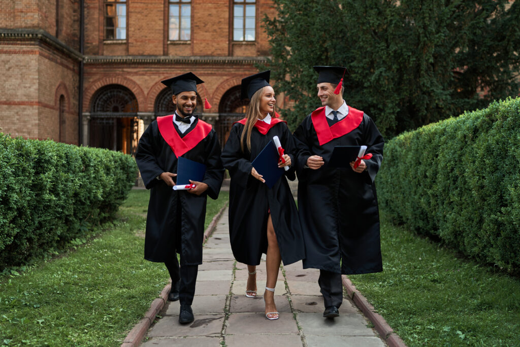 Students walking at graduation ceremony, new graduate jobs, companies hiring new grads.