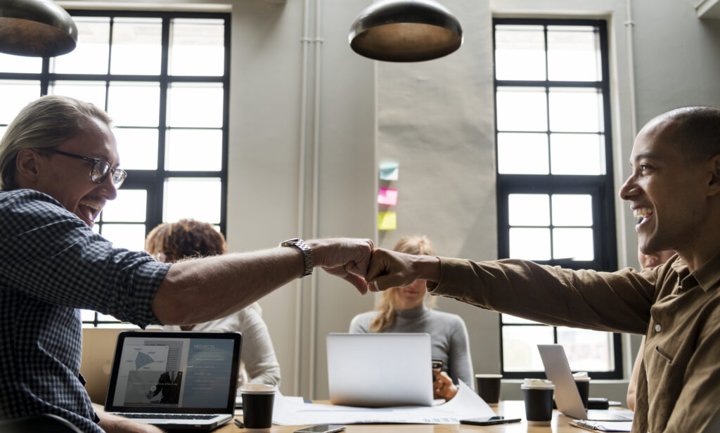 Two colleagues fist bumping, symbolizing successful integration in the best employee onboarding experience.