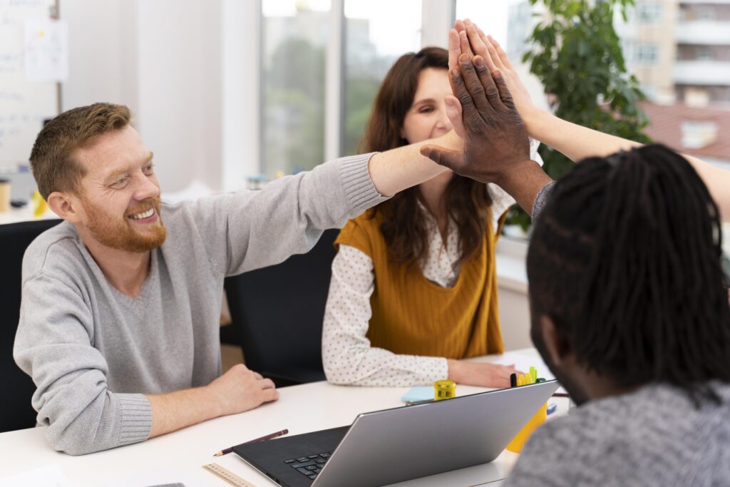 A diverse group of coworkers collaborating at a conference table, engaged in discussion and sharing positive feedback