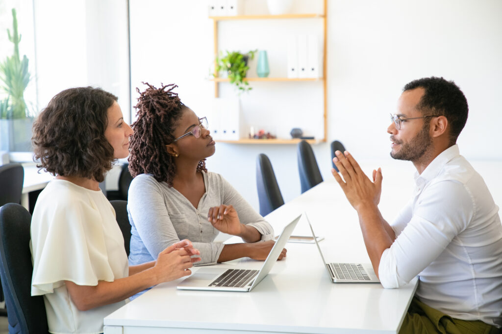 Burnout in HR. Three employees in a meeting, actively discussing employee feedback with a focus on mental health.