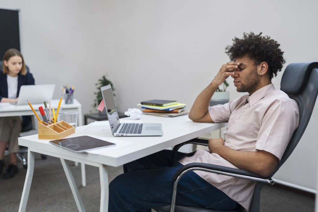 Male HR employee with a tired expression, sitting in a meeting room alone.