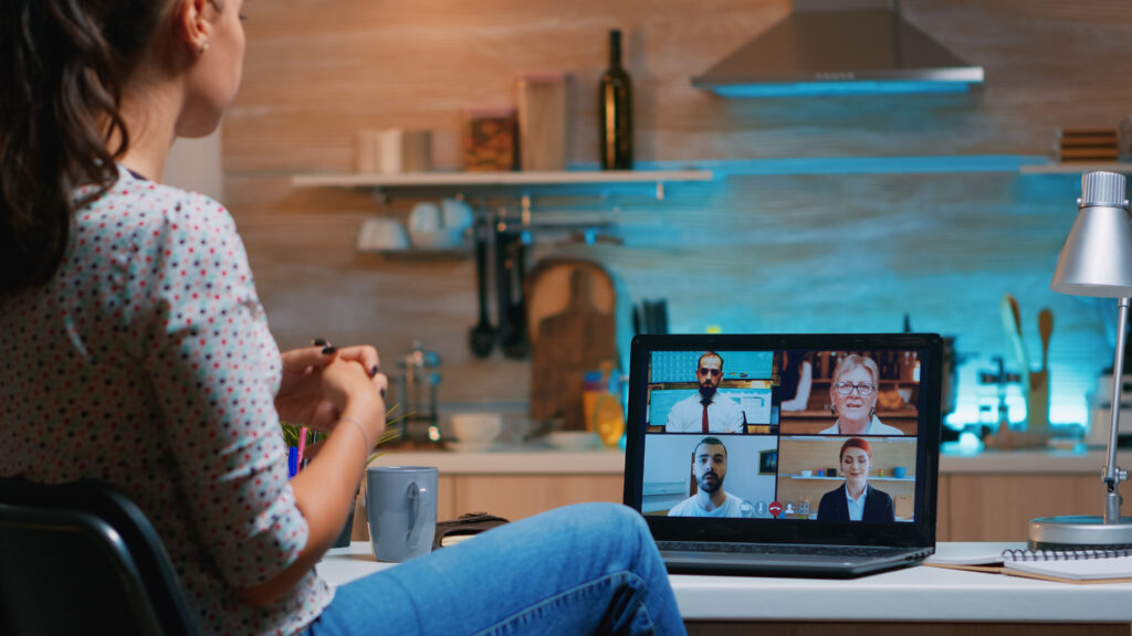 A woman working on her computer at home, engaged in a video call, symbolizing remote work challenges.