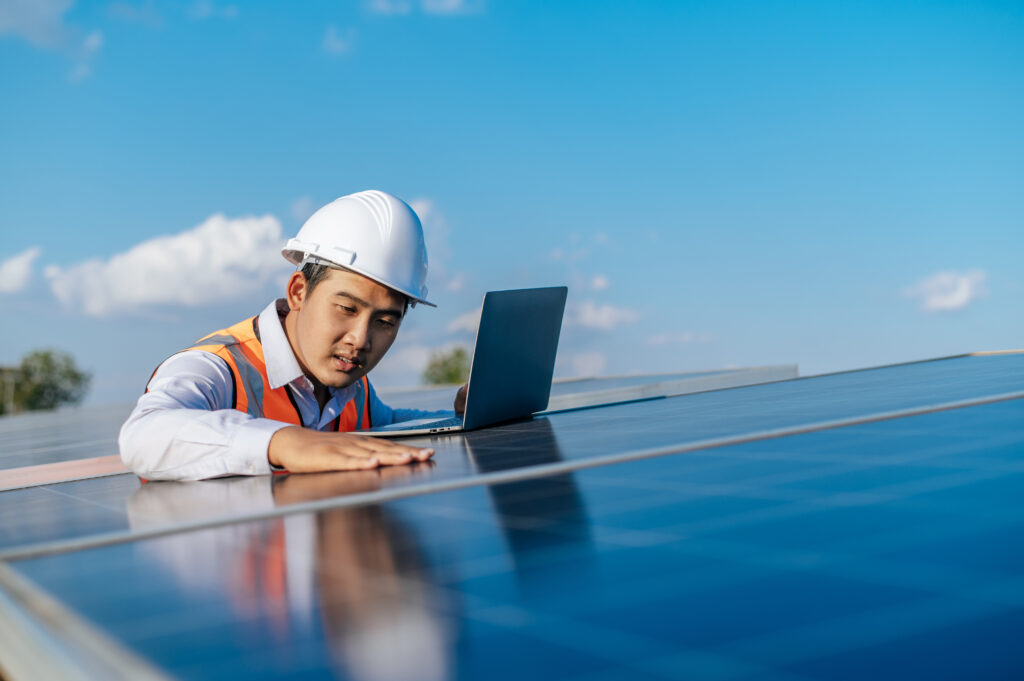 Man troubleshooting solar panel recruitment challenges using laptop on site