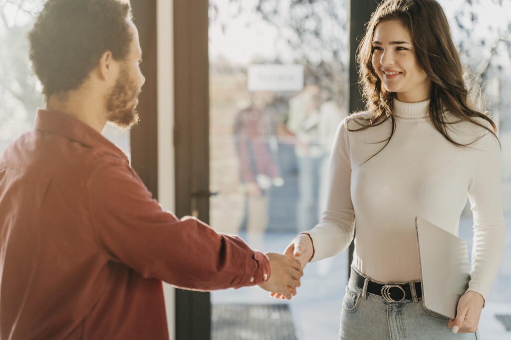 Successful candidate shaking hands with hiring manager thanks to social referrals.
