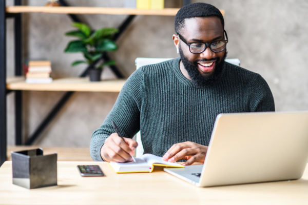 Man taking notes during his remote onboarding call.