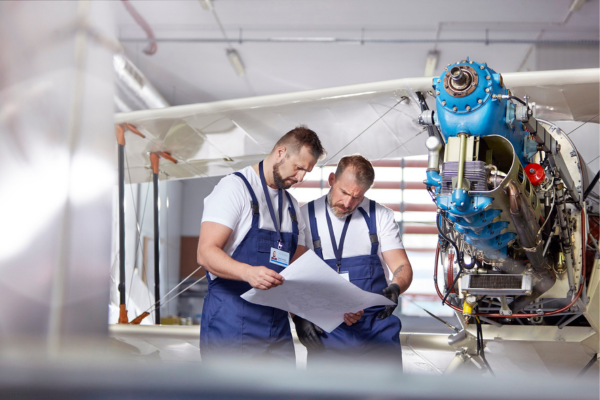 Aircraft mechanics reviewing technical plans in front of an airplane.