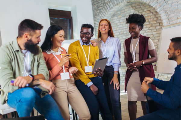 Diverse group of employees smiling and interacting in an open office space.