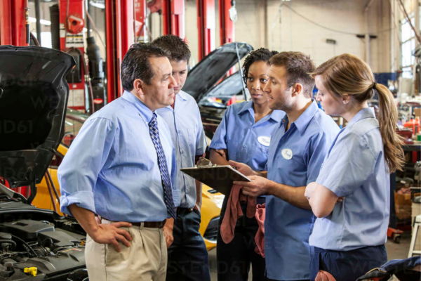 Automotive team meeting to discuss repair strategies in a workshop.