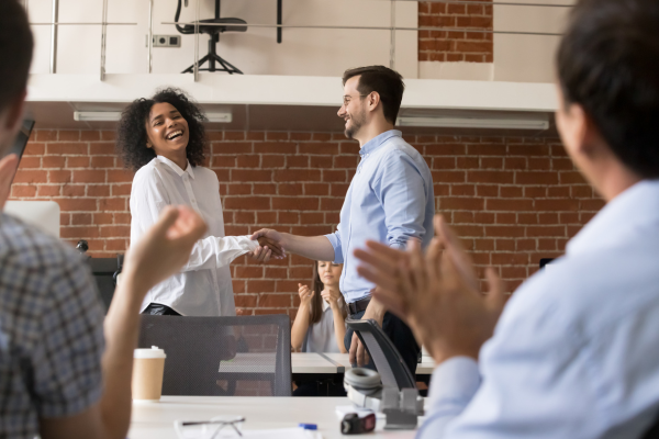 A recruiter shaking hands with a candidate, representing a positive candidate experience by balancing technology and human interaction.