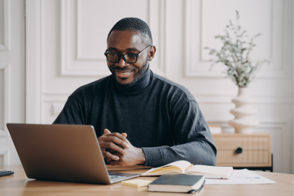 A remote worker smiling while using a laptop for an online interview, representing the future of online job recruiting.